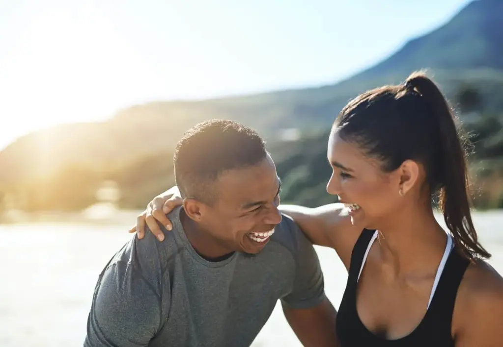 Couple in workout clothes laughing together outdoors