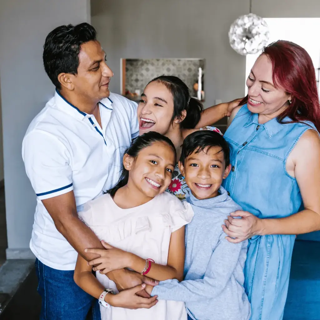 Parents and three children hugging and smiling at home