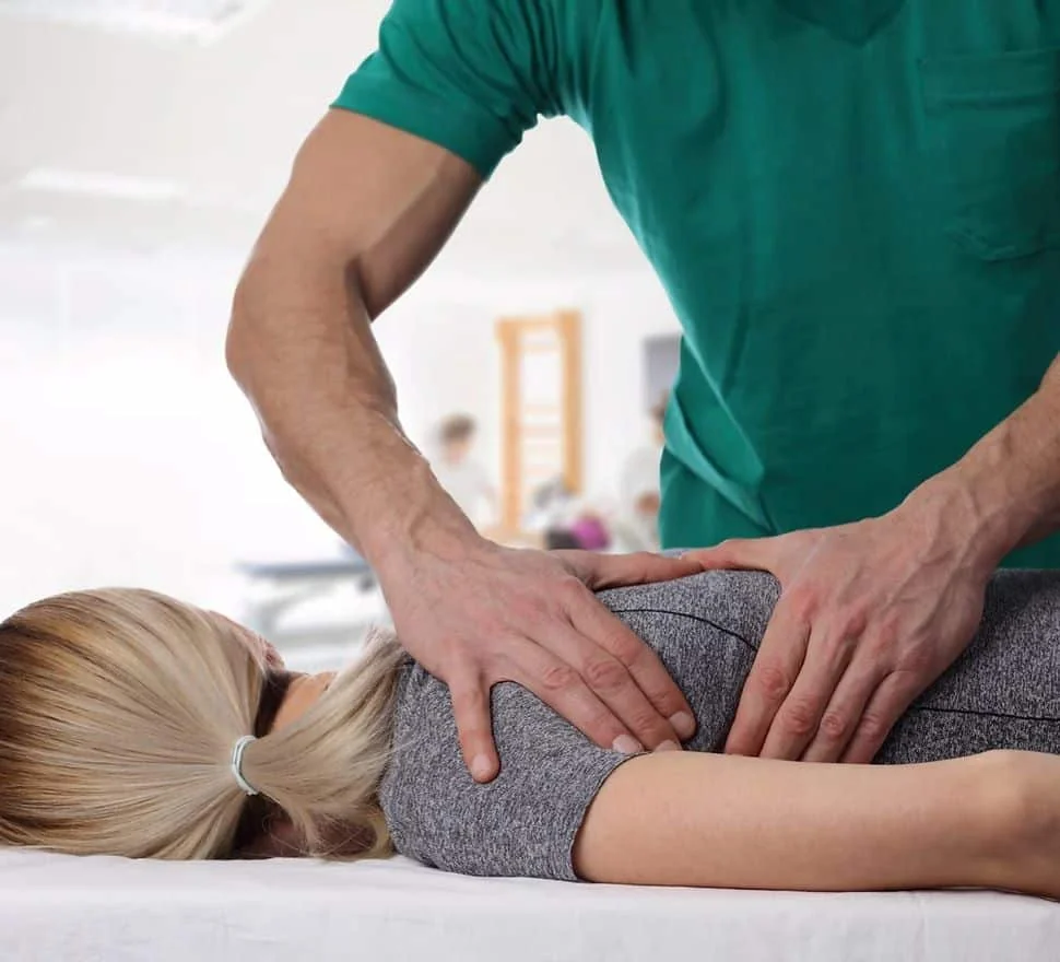 Practitioner pressing on the lower back of a patient lying face down